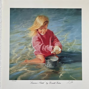 May include: A print titled "Summer's Child" by Donald Zolan. The artwork depicts a young child in a pink sweater playing in shallow water, holding a seashell. A small metal bucket sits nearby. The child's blonde hair is blowing in the wind.