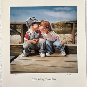 May include: A print titled "First Kiss" by Donald Zolan. The artwork depicts a young boy in a striped engineer's cap and overalls kissing a girl in a striped shirt and blue jeans. They are seated on a wooden dock with a lake in the background.