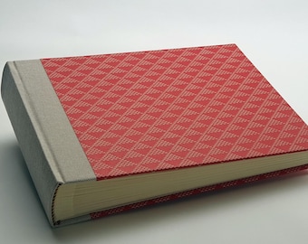 May include: A red photo album with a geometric pattern on the cover and a gray fabric spine.