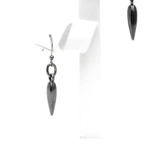 May include: A pair of dark gray earrings with a teardrop-shaped pendant. The earrings are suspended from a small silver hook and connected to the pendant by a small ring. The earrings are displayed on a white jewelry stand.