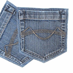 May include: Close-up of two blue denim jean pockets. The pockets have decorative stitching in a contrasting tan color. The denim has a classic, worn look, with visible vertical lines in the fabric.
