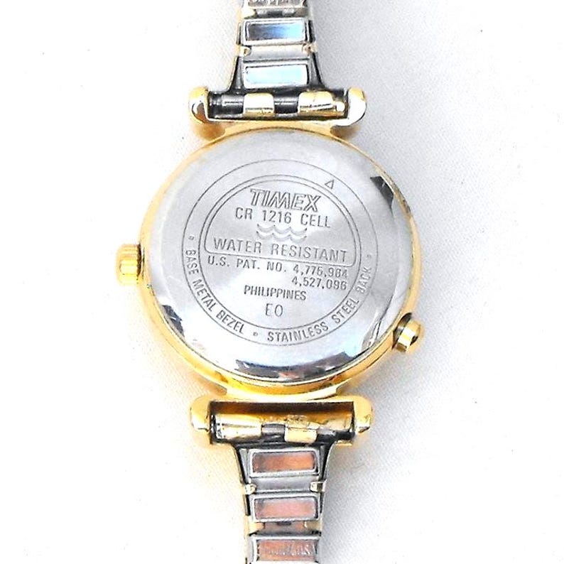 The case back is marked:  TIMEX, CR 1216 CELL, WATER RESISTANT, U.S. PAT. NO. 4,775,964, 4,527,096, PHILIPPINES, EO, BASE METAL BEZEL, STAINLESS STEEL BACK