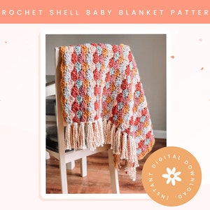 May include: A crocheted baby blanket with a shell stitch pattern in shades of pink, blue, green, and yellow. The blanket has a fringe border and is draped over a chair. The image includes the text "INSTANT DIGITAL DOWNLOAD".