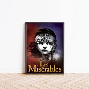 Op de afbeelding: Een zwart ingelijste poster met een rode, witte en blauwe achtergrond. De poster toont een zwart-witte illustratie van een jong meisje met een serieuze uitdrukking. De tekst "Les Misérables" staat in gouden letters onderaan de poster.
