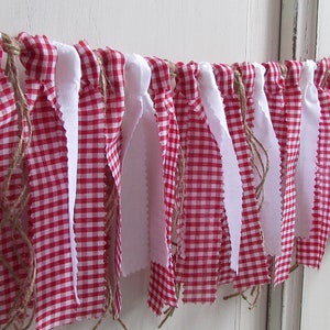 May include: A decorative banner featuring alternating red and white fabric strips. The red fabric has a classic gingham pattern, while the white strips are plain. The banner is strung on a natural twine, creating a rustic, country-style aesthetic.