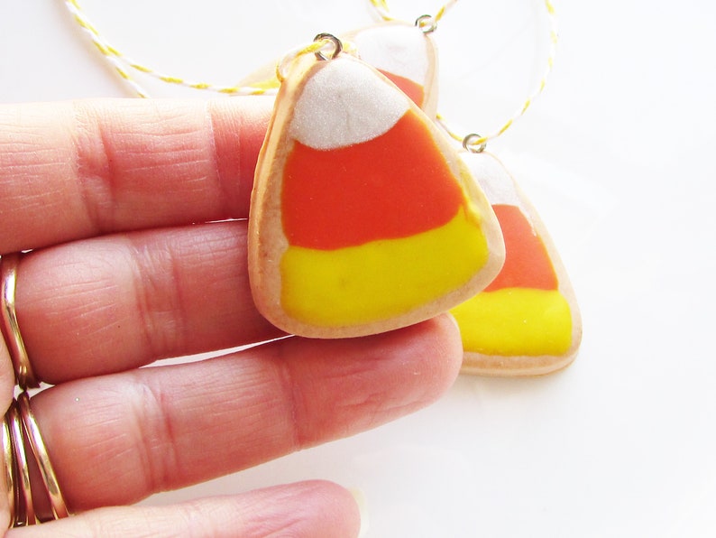 Puede incluir: Tres galletas hechas a mano con forma de ma&iacute;z dulce con glaseado blanco, naranja y amarillo. Las galletas est&aacute;n enhebradas en un cordel y est&aacute;n listas para colgarse como adornos.