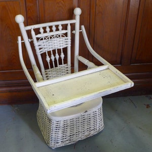 May include: White wicker high chair with a white tray. The chair has a woven wicker seat and back, and the tray is attached to the chair with metal brackets.