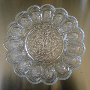 Peut inclure: Une assiette à œufs en verre transparent avec 12 compartiments individuels. L'assiette a un design texturé et perlé.