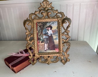 Ornate Victorian metal frame stand with vintage postcard