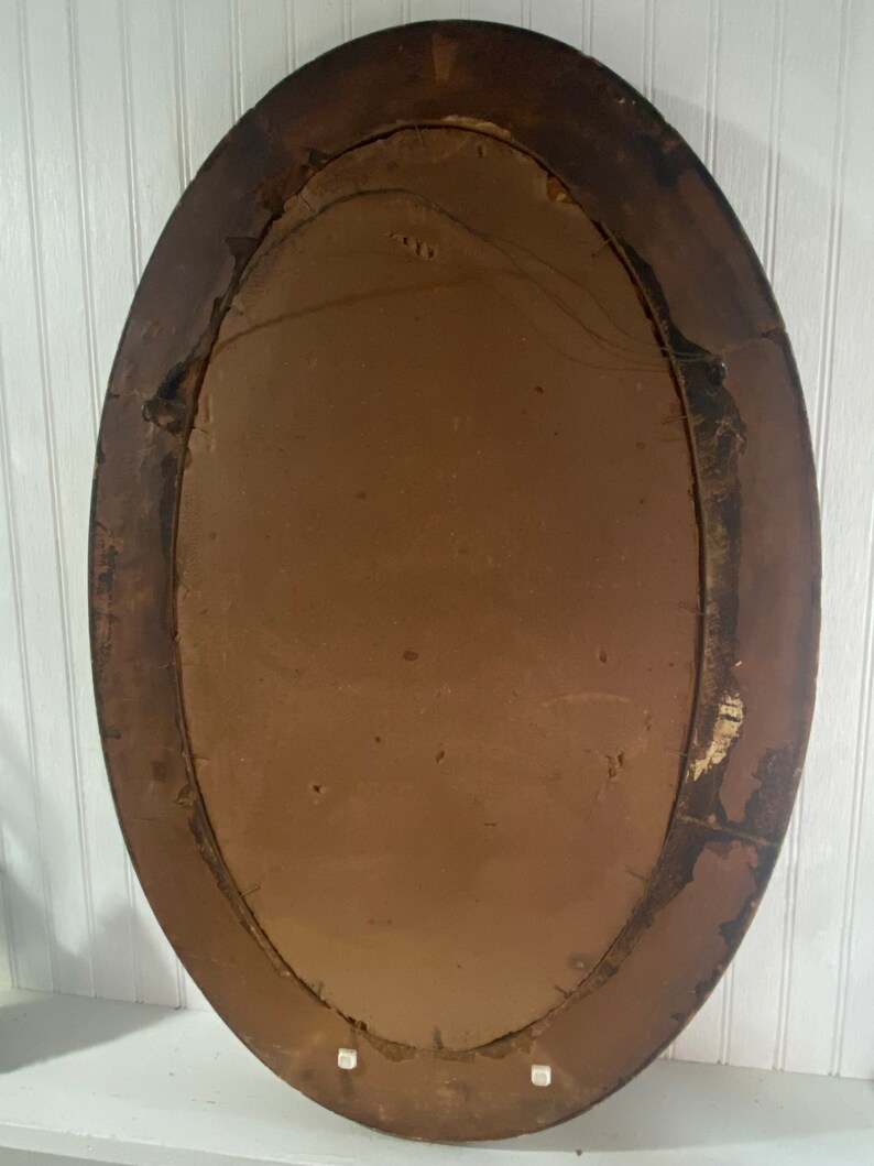 May include: An oval-shaped wooden picture frame with a brown finish. The frame has a simple design and is in good condition.