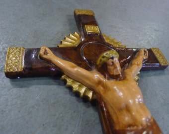 May include: A wooden crucifix with a brown and gold finish. The figure of Jesus Christ is depicted with a crown of thorns and a realistic, detailed body.
