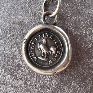 Peut inclure: Breloque en argent avec un design de sceau de cire représentant un coq et le texte "White Lily Grow".