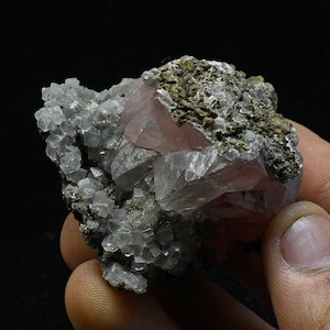 Könnte beinhalten: Ein Cluster aus rosafarbenen Fluoritkristallen mit glasartigem Glanz, eingebettet in eine Matrix aus grauem Gestein. Die Kristalle haben scharfe, gut definierte Flächen und ein durchscheinendes Aussehen.