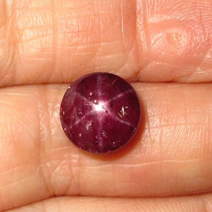 May include: A deep red star ruby gemstone with a six-pointed star in the center.