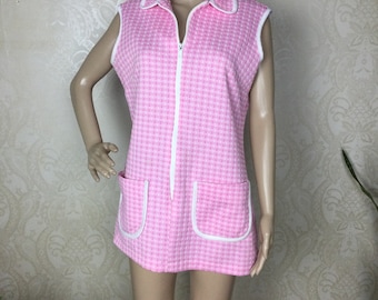 May include: A pink and white gingham sleeveless dress with a white zipper down the front and white trim around the collar and pockets.