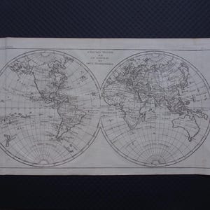May include: Antique world map print featuring two hemispheres, with detailed geographical features. The map is printed in black ink on aged paper, showcasing continents, oceans, and cartographic details. The title is in French.