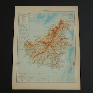 May include: A vintage map of Borneo, featuring detailed topographical information. The map uses a color scheme to indicate elevation, with shades of brown and orange highlighting mountainous regions. The title "BORNEO" is printed at the top.