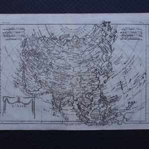 May include: An antique map of Asia, printed in black ink on aged paper. The map displays detailed geographical features, with intricate lines and text labels. The title "L'Asie" is visible. The rectangular map is likely from a historical atlas, offering a glimpse into the past.