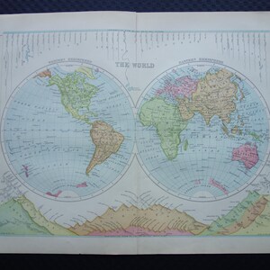 Puede incluir: Un mapa antiguo del mundo, con dos hemisferios con continentes en tonos verdes, rosas y amarillos. El título "THE WORLD" está centrado en la parte superior. El mapa está impreso en papel envejecido con un océano azul claro.