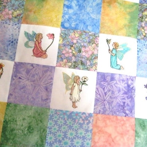 May include: A patchwork quilt with a floral design and embroidered fairies. The quilt is made of different fabrics in shades of blue, green, purple, and yellow. Each square features a different fairy design.