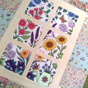 May include: A floral quilt featuring a window design with six squares, each showcasing a different flower and insect illustration. The flowers include pink, purple, and yellow blooms, with a hummingbird, butterfly, and bee. The quilt has a cream-colored border.