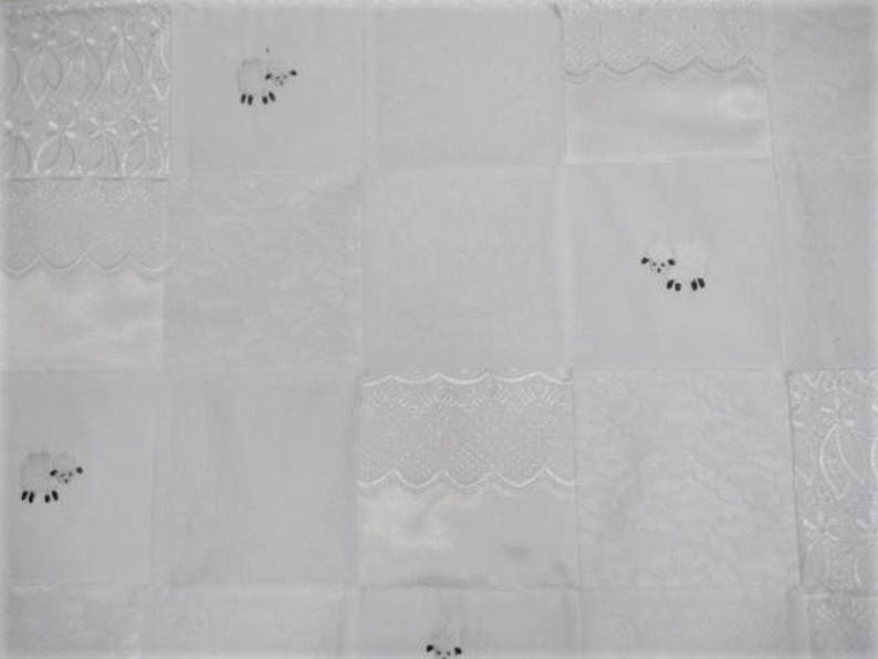 K&ouml;nnte beinhalten: Wei&szlig;e Steppdecke mit Patchwork-Design mit gestickten Schafen und Spitzenbesatz.