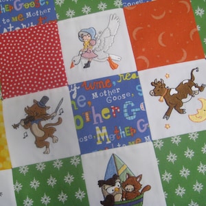 May include: A colorful patchwork quilt with embroidered images of animals and text. The text includes "Mother Goose" and "Old to me Mother Goose".