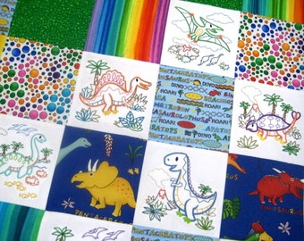 Puede incluir: Una colcha colorida con temática de dinosaurios. Cada cuadrado presenta un dinosaurio diferente, incluyendo un estegosaurio, un triceratops y un pterodáctilo. La colcha está hecha de tela blanca con dinosaurios bordados de colores y texto.
