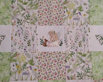 Puede incluir: Una colcha de patchwork con cuadrados alternos de estampados botánicos y tela blanca. Los cuadrados blancos muestran diseños bordados de un hada con un conejo y dos mariposas con alas florales. Los estampados botánicos incluyen follaje verde, pequeñas flores rosas y flores silvestres amarillas.