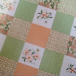 May include: A patchwork quilt with a floral design. The quilt is made of different fabrics in shades of green, pink, and white. The quilt features a repeating pattern of flowers and leaves.