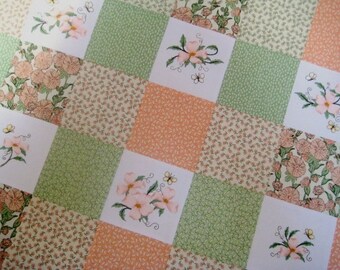 Puede incluir: Una colcha de retazos con un diseño floral. La colcha está hecha de diferentes telas en tonos de verde, rosa y blanco. La colcha presenta un patrón repetitivo de flores y hojas.