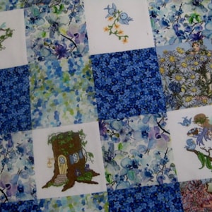 May include: A patchwork quilt with a blue and white floral pattern. The quilt is made up of squares with different designs, including a tree house, a fairy, and a bird's nest.