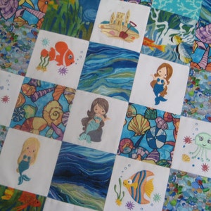 May include: A white quilt with a patchwork design featuring various sea creatures, including a seahorse, a jellyfish, a fish, and mermaids. The quilt is made of white fabric with a blue and white wave pattern.