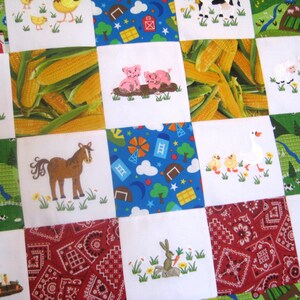 May include: A colorful patchwork quilt with various farm animal and country-themed designs. The quilt features a variety of animals, including pigs, cows, horses, ducks, and chickens. The quilt also features a variety of country-themed designs, including corn, barns, and tractors.