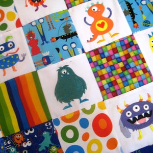 May include: A colorful patchwork quilt with a variety of monster designs. The quilt is made of squares of different fabrics, each with a different monster design. The monsters are all different colors and have different features, such as horns, eyes, and teeth.
