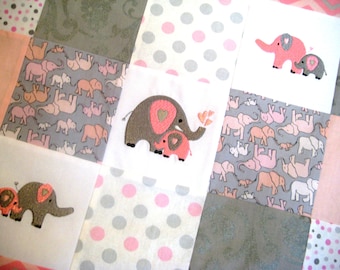 Puede incluir: Una colcha de bebé rosa y gris con un diseño de patchwork que presenta elefantes bordados con corazones. La colcha está hecha de tela suave y es perfecta para una guardería.