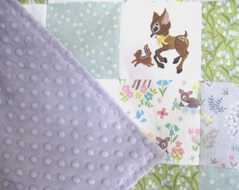 Könnte beinhalten: Eine Babydecke mit einer lilafarbigen Minky-Rückseite und einer Patchwork-Vorderseite. Die Vorderseite zeigt eine Vielzahl von Stoffen mit Blumen- und Tiermotiven, darunter ein Reh und ein Eichhörnchen.