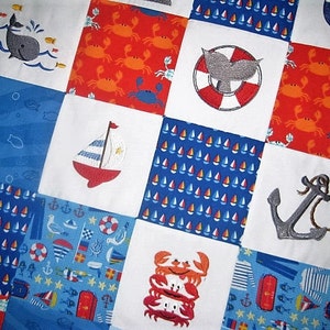 May include: A patchwork quilt with a nautical theme. The quilt is made of various fabrics with different patterns, including blue and white sailboats, red and white crabs, and a blue and white anchor. The quilt is perfect for a baby's nursery or a child's bedroom.