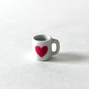 May include: White ceramic mug with a pink heart design.