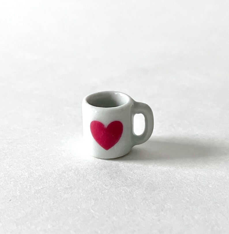May include: White ceramic mug with a pink heart design.