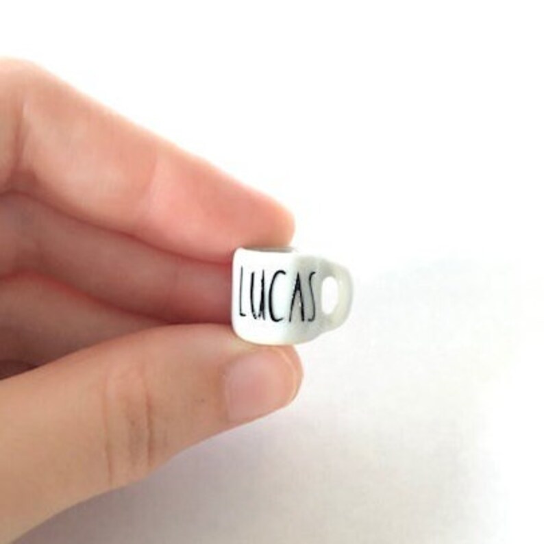 May include: A small white ceramic mug with a black handle and the name "Lucas" written on the front.