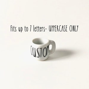 May include: White ceramic mug with a black "CUSTOM" inscription. Fits up to 7 letters - UPPERCASE ONLY.