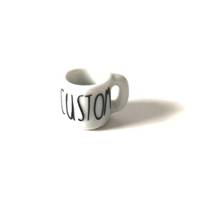 May include: White ceramic mug with a black "CUSTOM" inscription.