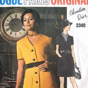 May include: A vintage Vogue Paris Original sewing pattern featuring a woman in a mustard yellow dress with a black belt and buttons. The pattern is labeled "Christian Dior 2340" and includes a drawing of a woman in a black dress.