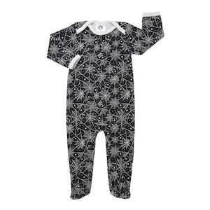 May include: Black and white baby footed sleeper with a spiderweb and star pattern. The sleeper has long sleeves, a white collar, and white cuffs. The garment is designed for infants and toddlers.