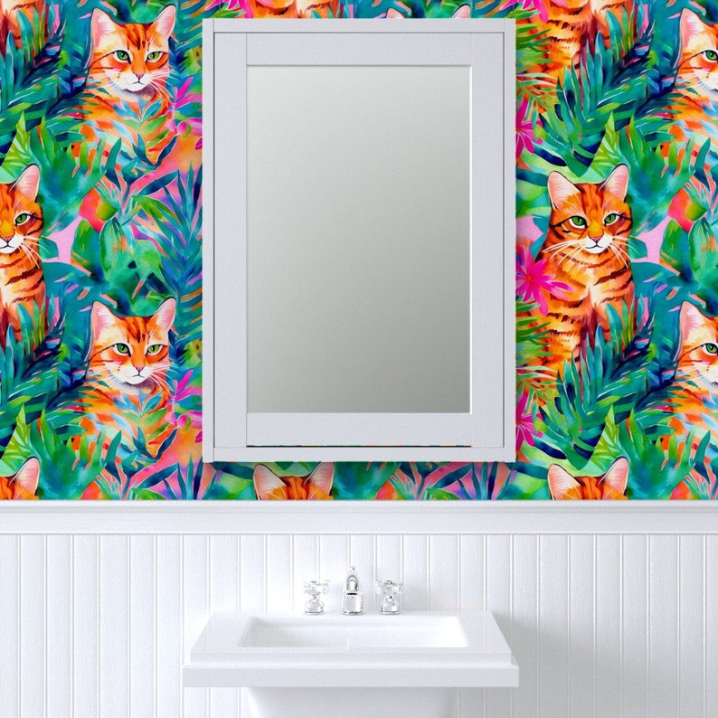 May include: A white bathroom vanity with a mirror above the sink. The walls are covered in a colorful wallpaper featuring orange cats and tropical leaves.