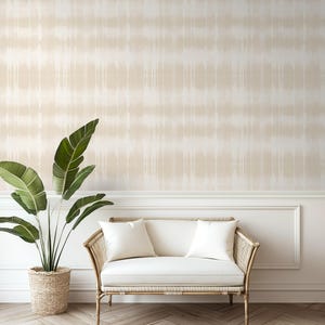 May include: A white couch with two white pillows sits in front of a wall with a beige and white tie-dye pattern wallpaper. A large green plant is in a woven basket to the left of the couch.