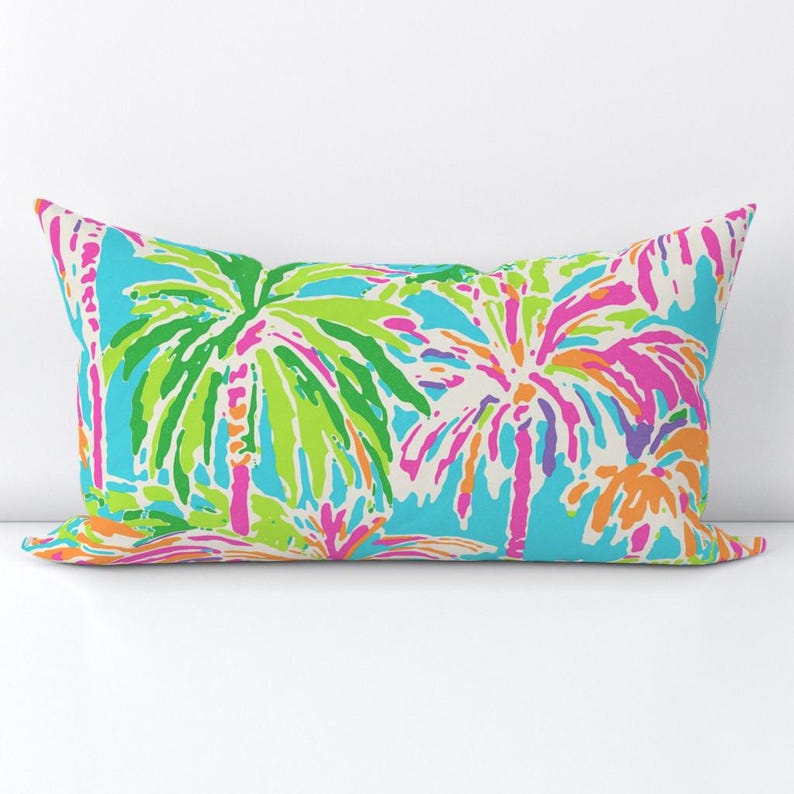 Pu&ograve; includere: Un cuscino rettangolare con un motivo luminoso e colorato di palme su uno sfondo blu chiaro. Le palme sono contornate di verde, rosa, arancione e viola.