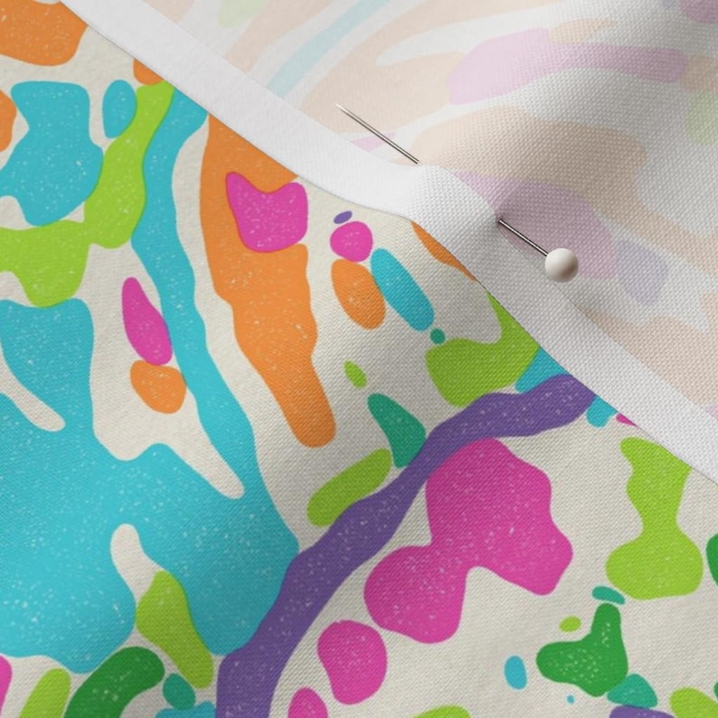 Pu&ograve; includere: Primo piano di un tessuto con un motivo astratto colorato. Il tessuto presenta uno sfondo bianco con forme grandi e irregolari in tonalit&agrave; di blu, verde, rosa, arancione e viola.
