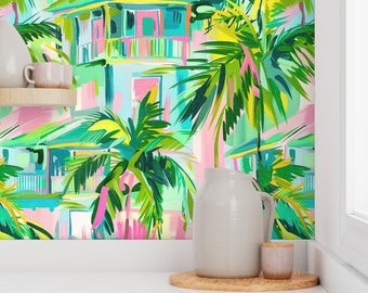 May include: Colorful wallpaper featuring a tropical scene with houses, palm trees, and vibrant brushstrokes in shades of pink, green, blue, and yellow. A white pitcher, a small wooden tray, and a pink cup are in the foreground.